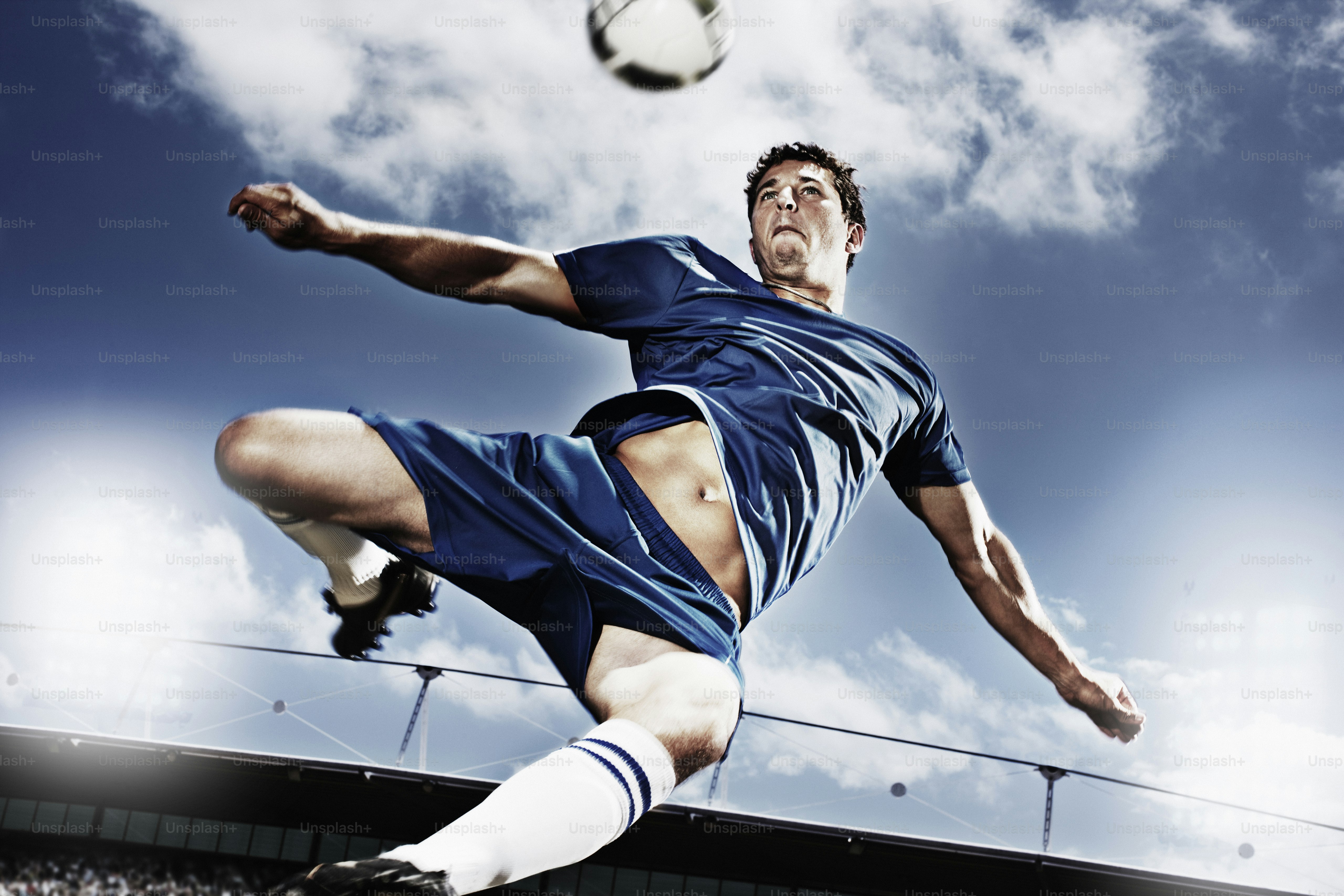 a man kicking a soccer ball on top of a field